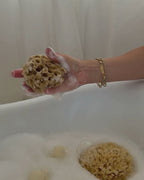 natural sea sponge in hand with lather over baby bath